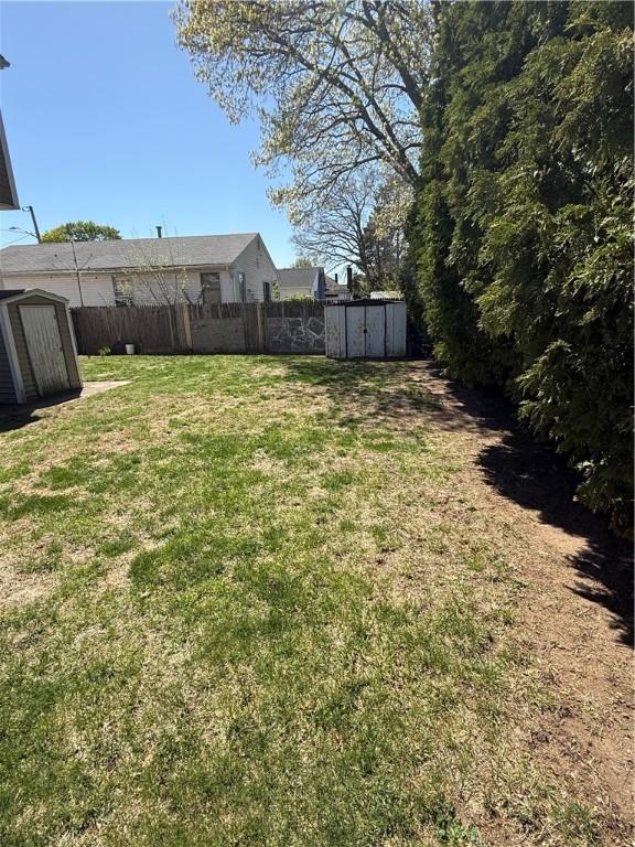 view of yard featuring fence, an outbuilding, and a shed