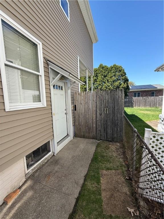 property entrance with a lawn and fence