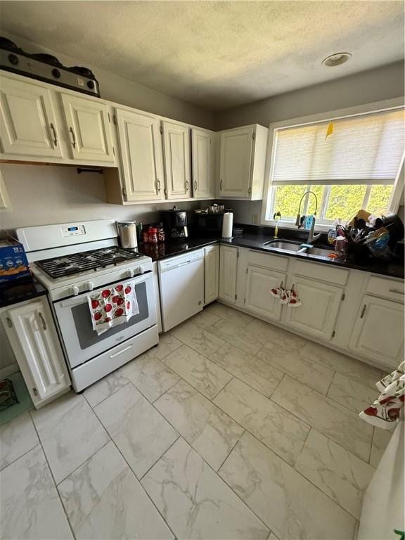 kitchen with white cabinets, dark countertops, white appliances, a textured ceiling, and marble finish floor