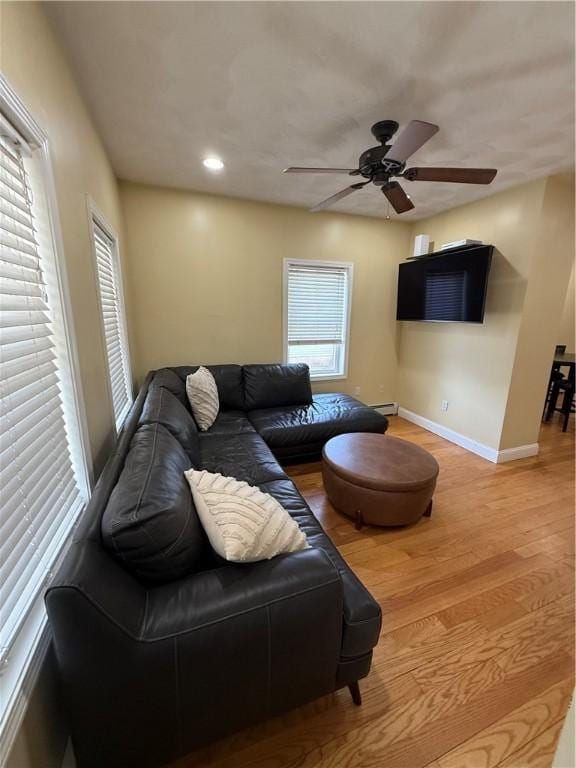 living room featuring ceiling fan, baseboard heating, wood finished floors, baseboards, and recessed lighting