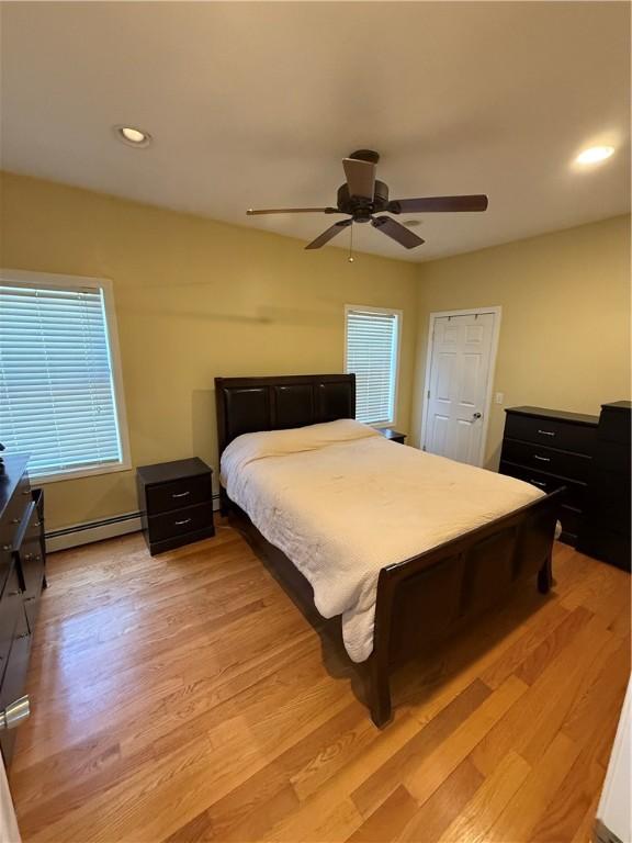 bedroom with recessed lighting, ceiling fan, baseboard heating, and light wood-type flooring