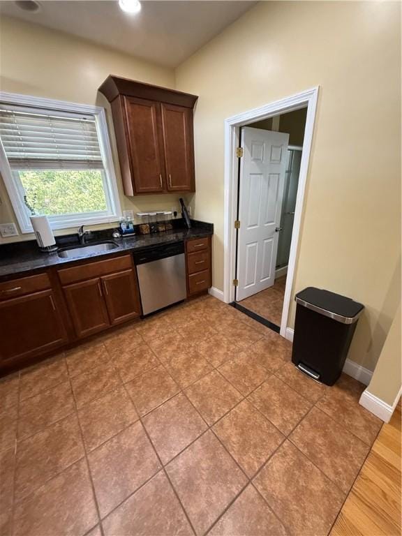 kitchen featuring dark countertops, stainless steel dishwasher, a sink, baseboards, and recessed lighting