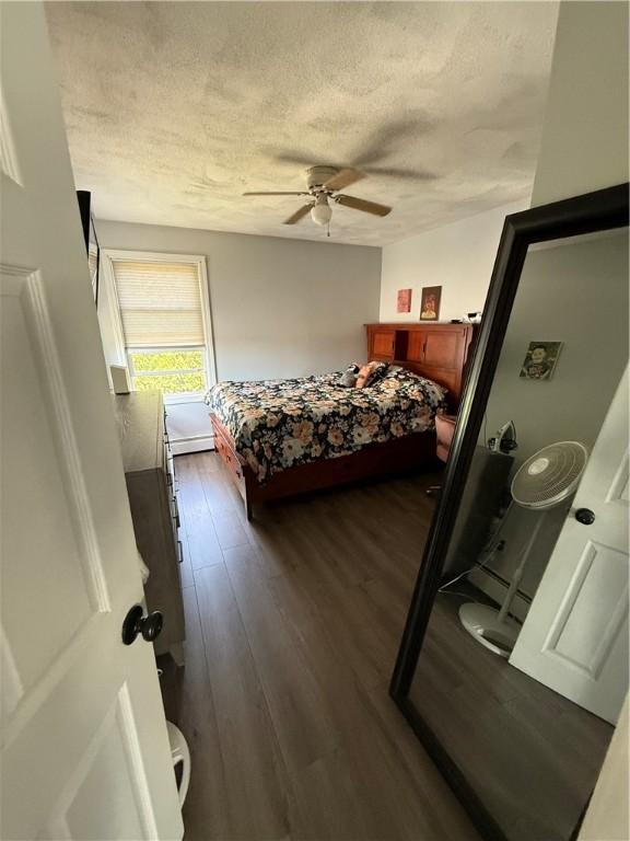 bedroom with a ceiling fan, a textured ceiling, and dark wood-style flooring
