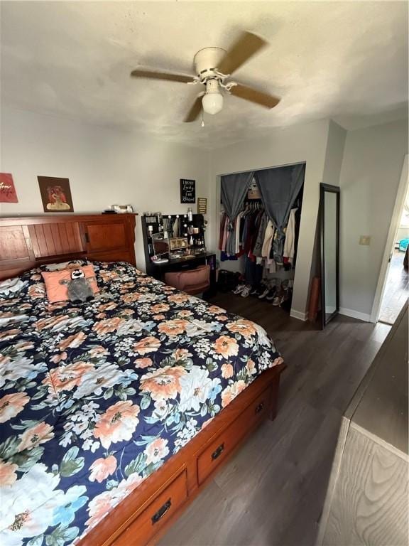 bedroom with a ceiling fan, baseboards, dark wood finished floors, and a closet
