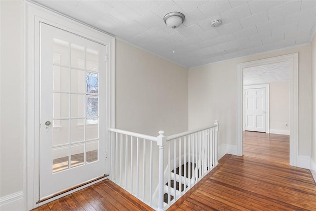 hall featuring crown molding, baseboards, an upstairs landing, and hardwood / wood-style floors