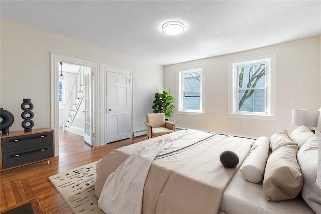 bedroom with wood finished floors and a baseboard radiator