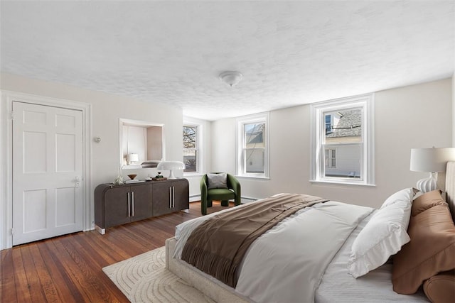 bedroom featuring a textured ceiling, a baseboard radiator, and wood finished floors