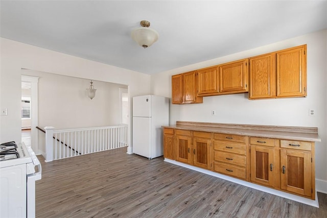 kitchen featuring white appliances, brown cabinets, wood finished floors, and light countertops