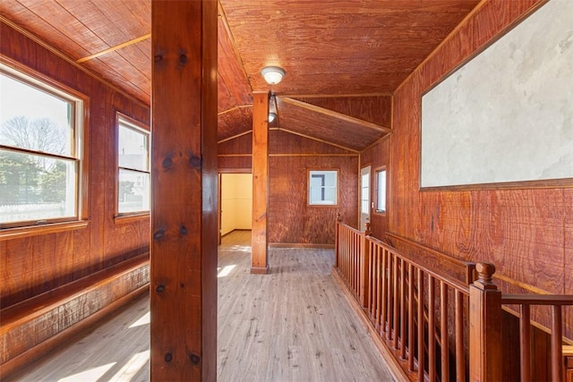 hall featuring light wood-style floors, wood ceiling, wood walls, and lofted ceiling