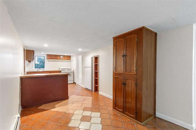 kitchen featuring a peninsula, white appliances, a textured ceiling, a baseboard heating unit, and brown cabinets