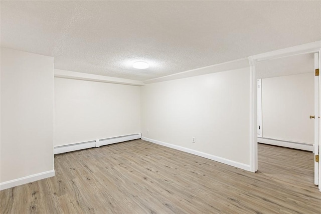 empty room featuring baseboards, a textured ceiling, wood finished floors, and baseboard heating