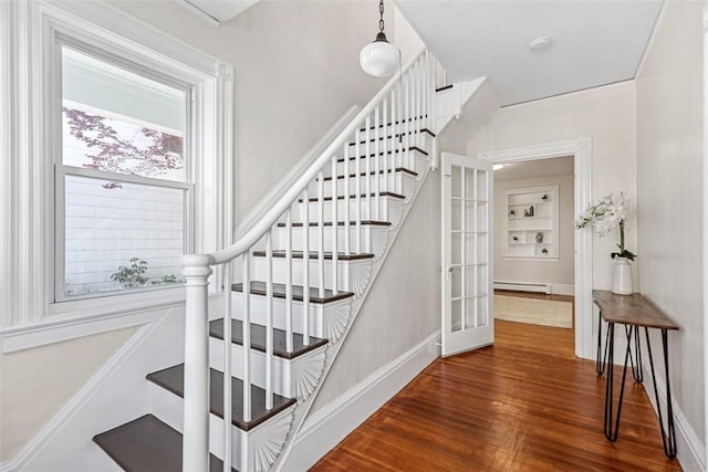 staircase featuring baseboard heating, baseboards, and wood finished floors