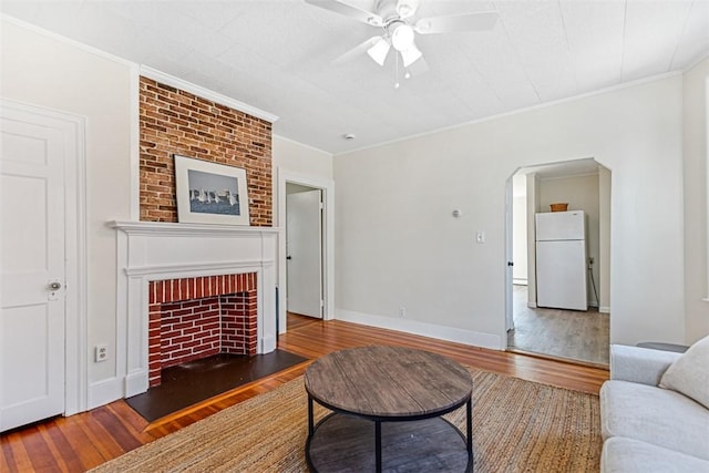 living room with arched walkways, a ceiling fan, wood finished floors, and ornamental molding