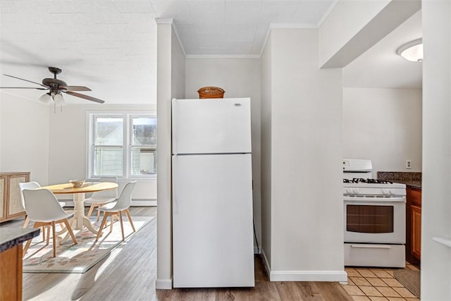kitchen with dark countertops, ornamental molding, white appliances, and light wood-style flooring