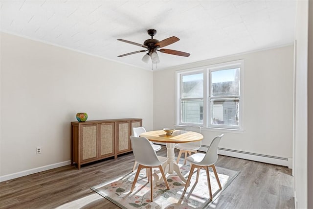 dining area featuring crown molding, a ceiling fan, a baseboard radiator, and light wood-style floors