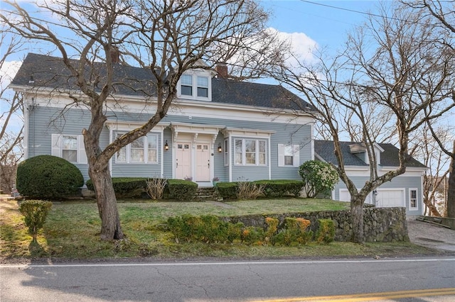 view of front facade with a garage, a front lawn, and a chimney
