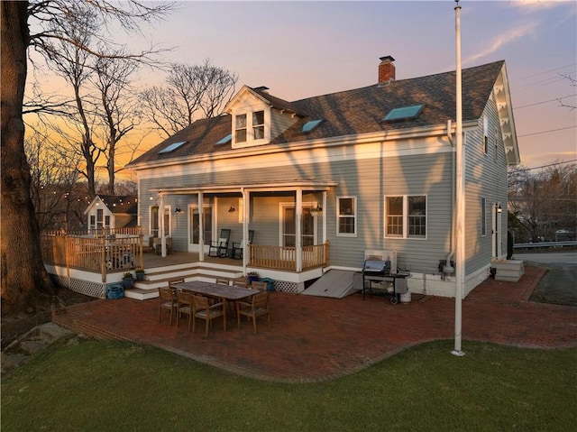 back of house featuring a yard, a deck, a chimney, and a patio area