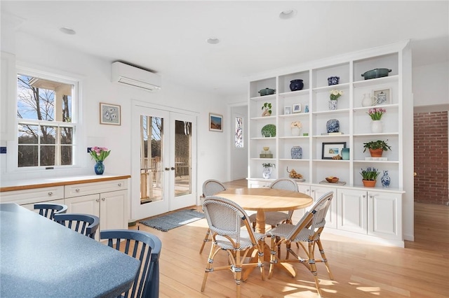 dining area with light wood-type flooring, french doors, and a wall mounted air conditioner