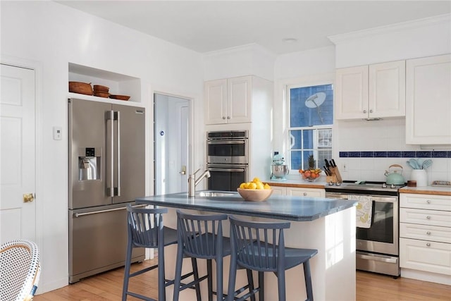 kitchen with light wood-style floors, white cabinets, a breakfast bar, and stainless steel appliances