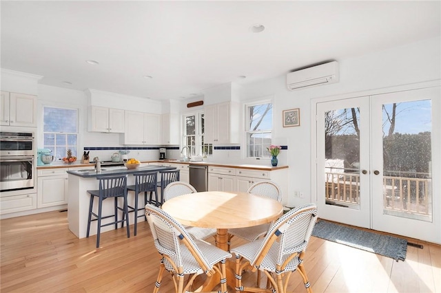 dining area with visible vents, a wall mounted air conditioner, recessed lighting, light wood-type flooring, and french doors