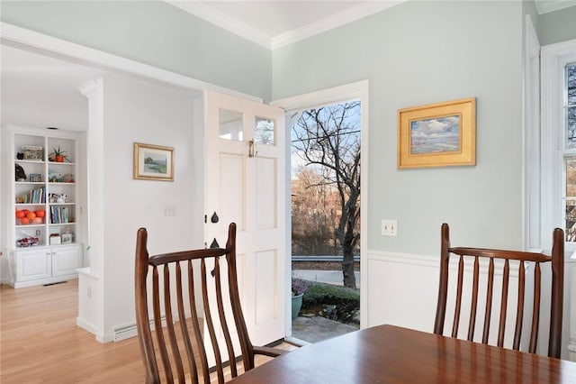 dining area featuring wainscoting, ornamental molding, built in shelves, and light wood-type flooring