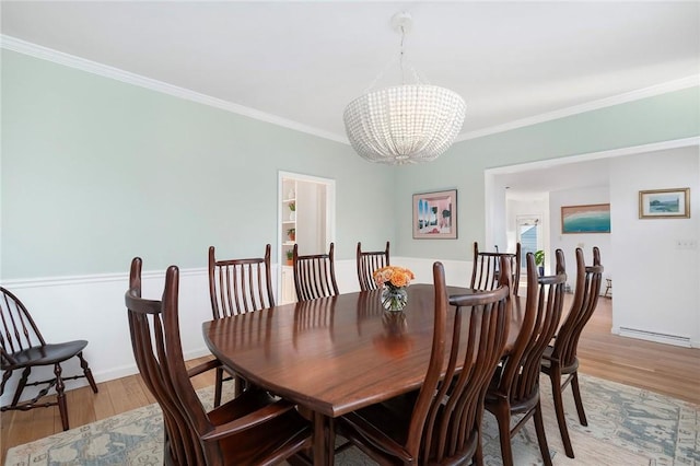 dining space with a chandelier, ornamental molding, and light wood finished floors
