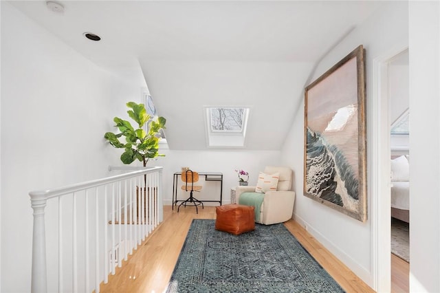 interior space featuring baseboards, wood finished floors, and vaulted ceiling with skylight