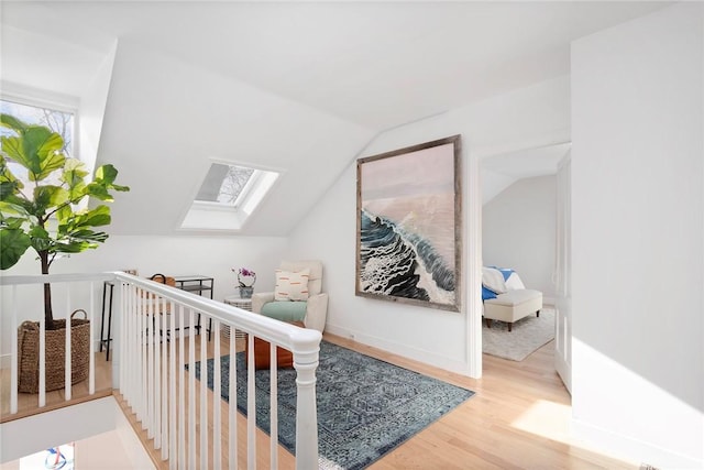 bonus room with lofted ceiling with skylight and wood finished floors