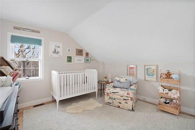 bedroom with visible vents, baseboards, a crib, and lofted ceiling