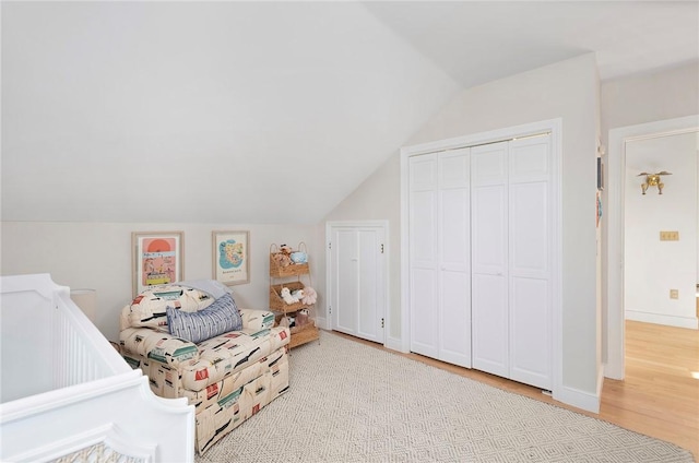 bedroom with baseboards, wood finished floors, lofted ceiling, and a closet