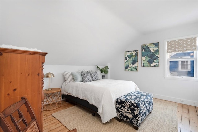 bedroom with baseboards, lofted ceiling, and hardwood / wood-style floors