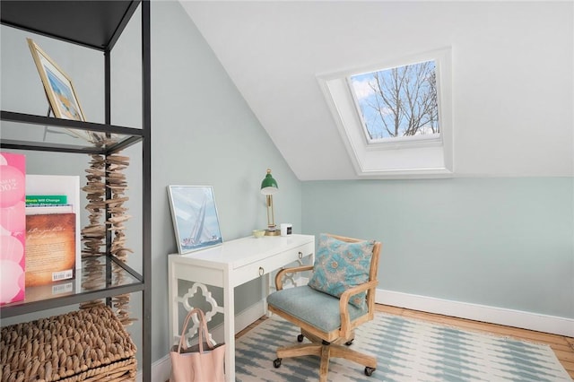 office space featuring baseboards, lofted ceiling with skylight, and wood finished floors