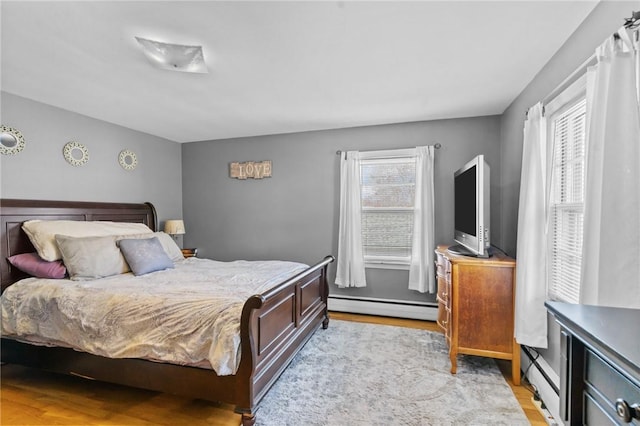bedroom with a baseboard radiator and light wood finished floors