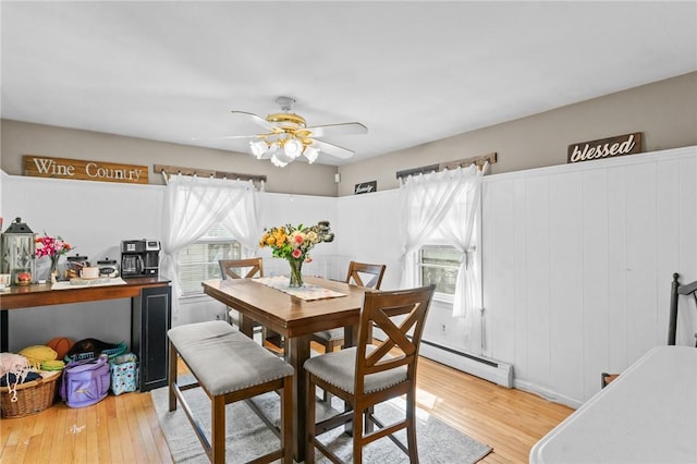 dining room featuring a baseboard radiator, a ceiling fan, and light wood-type flooring