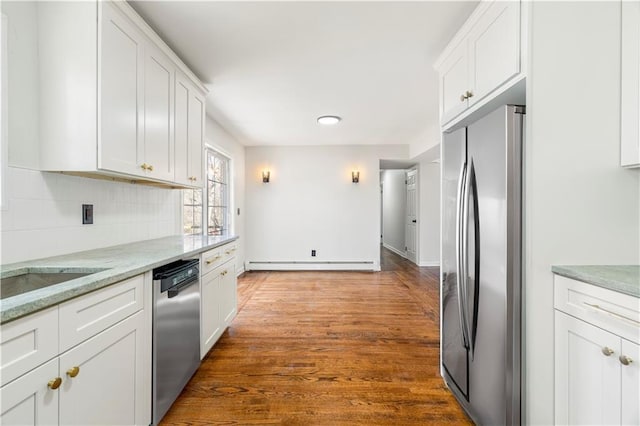kitchen featuring decorative backsplash, light stone countertops, white cabinets, a baseboard radiator, and appliances with stainless steel finishes