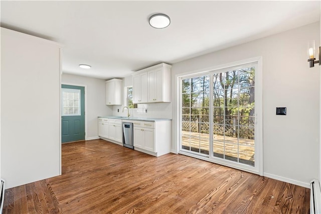 kitchen featuring baseboard heating, wood finished floors, dishwasher, a sink, and light countertops