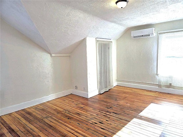 168 Spring St, Woonsocket, RI 02895 - bonus room featuring lofted ceiling, baseboards, a wall mounted air conditioner, a textured ceiling, and hardwood / wood-style flooring