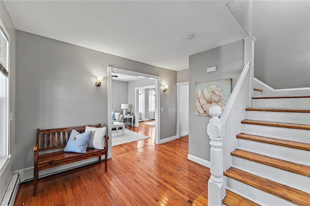 stairs with baseboards, a baseboard radiator, and hardwood / wood-style flooring