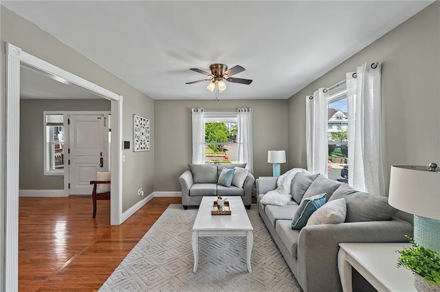 living room featuring baseboards, ceiling fan, and wood finished floors