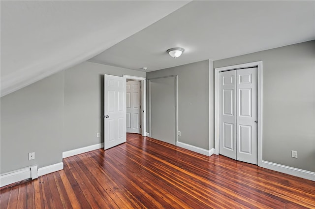 unfurnished bedroom featuring wood-type flooring, a closet, baseboards, and a baseboard radiator