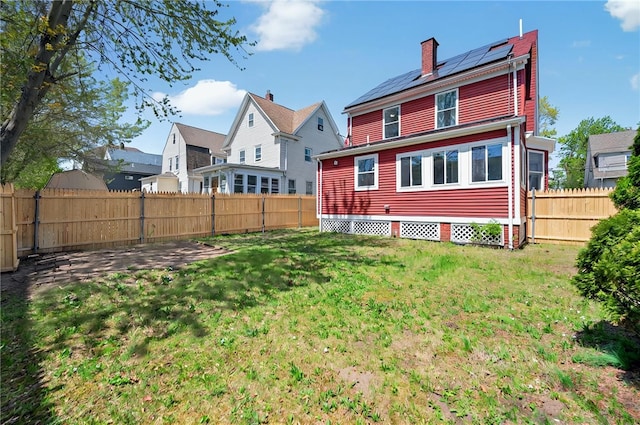rear view of house with a yard, a chimney, and a fenced backyard