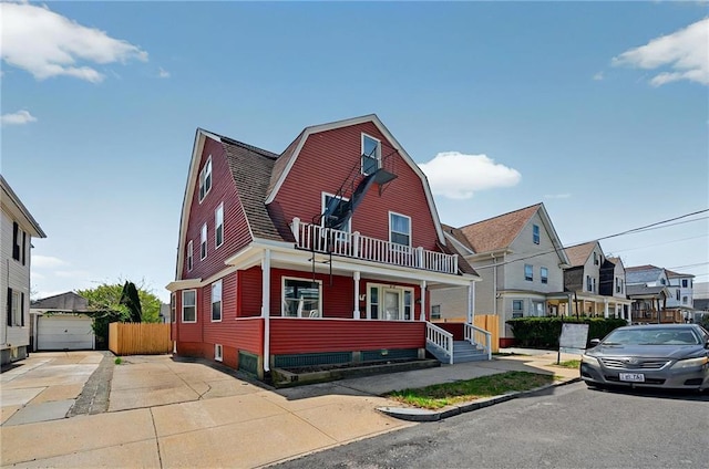 dutch colonial with a porch, a residential view, a balcony, and a gambrel roof