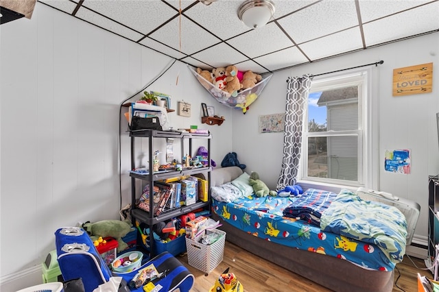 bedroom with a drop ceiling and wood finished floors