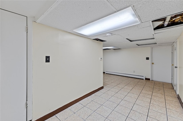 spare room with light tile patterned floors, a drop ceiling, and baseboard heating