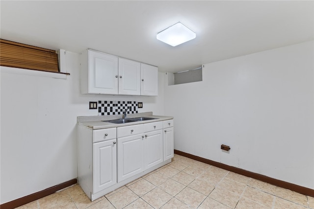 laundry area with light tile patterned flooring, baseboards, and a sink