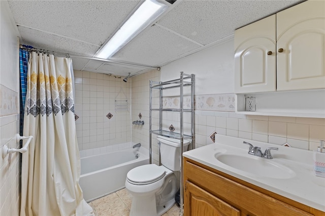 full bathroom with vanity, toilet, tile walls, a paneled ceiling, and shower / bath combo