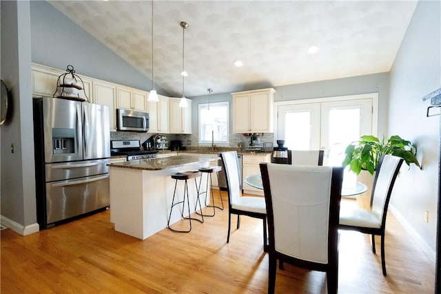 32 Dike St, Woonsocket, RI 02895 - kitchen with a kitchen breakfast bar, stainless steel appliances, decorative backsplash, light wood-type flooring, and a kitchen island