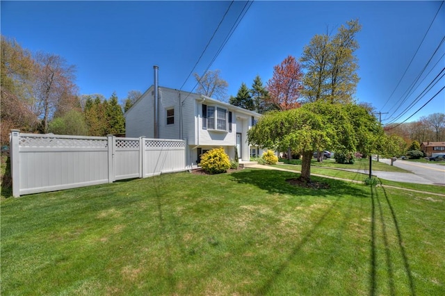 view of property exterior with fence and a yard