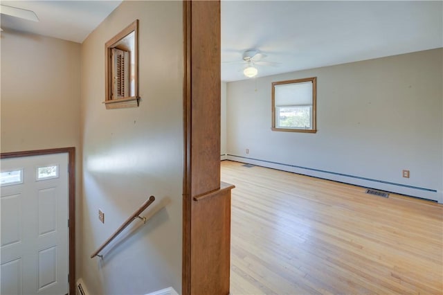 foyer entrance with a baseboard radiator, ceiling fan, and wood finished floors