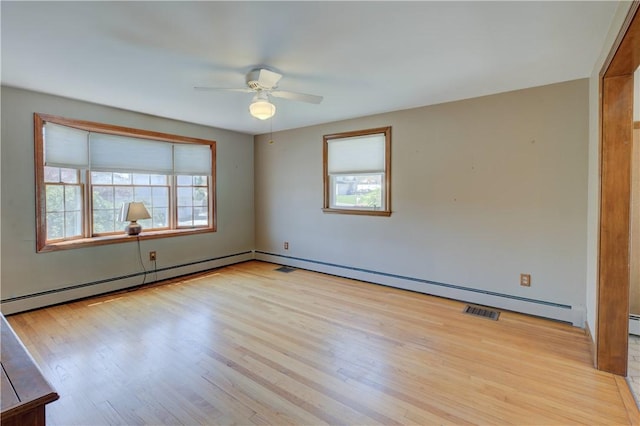 spare room with ceiling fan, baseboard heating, light wood finished floors, and visible vents